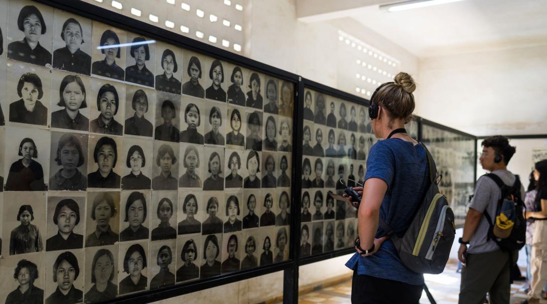 Two people look at a huge collection of images of those killed in the Killing Fields