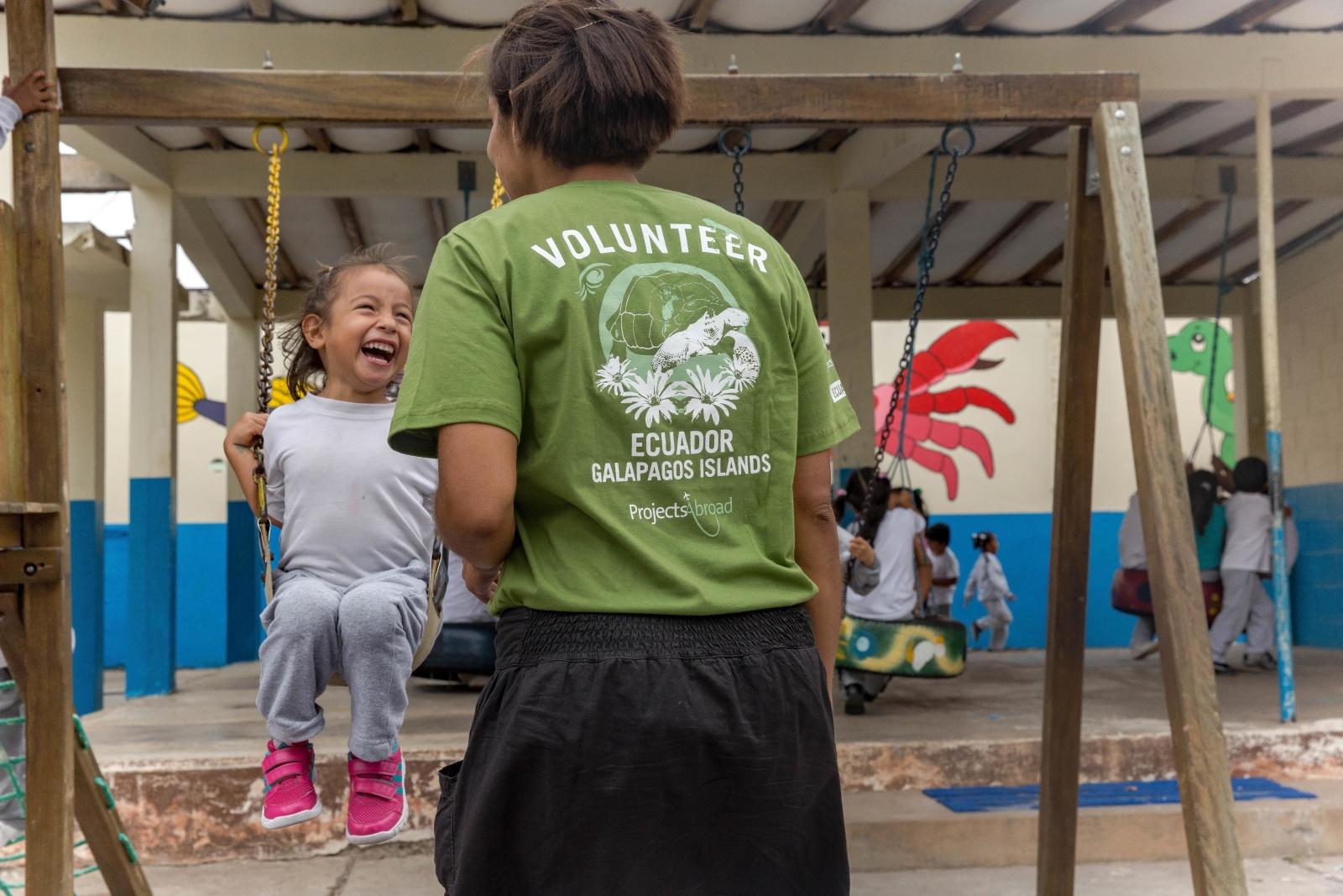 Volunteer and young girl play outside on a childcare project in Ecuador.