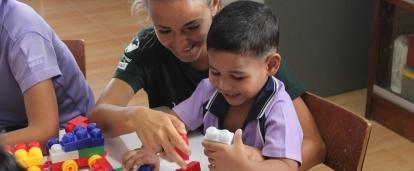 Une volontaire lors d'une mission humanitaire à l'étranger travaille avec un enfant et l'aide à construire des légos. 