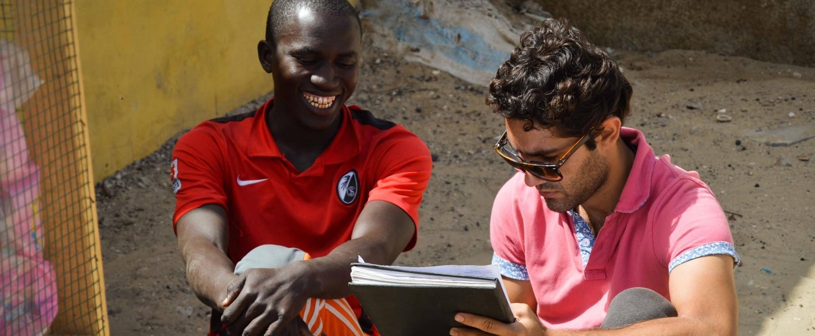 A Senegalese beneficiary discusses his business with a student doing a Micro-finance internship abroad.