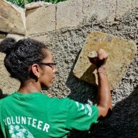 Voluntaria de construcción ayudando a enyesar una pared.