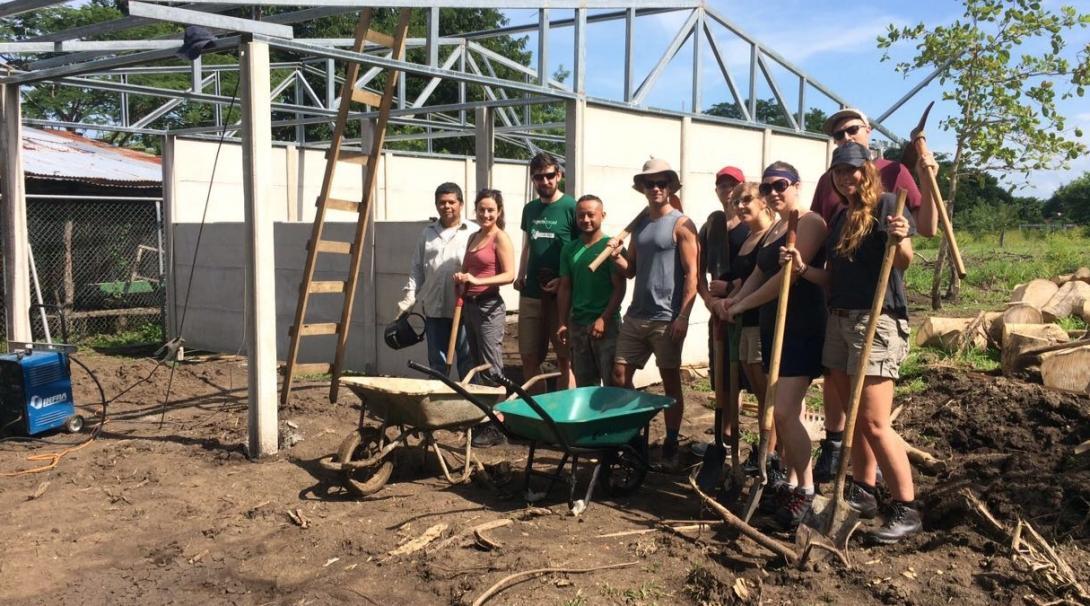 Des volontaires Projects Abroad construisent un bâtiment pendant leur mission humanitaire en groupe. 