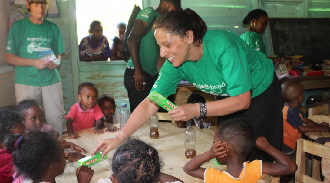 A volunteer abroad over 50 helps distribute toothpaste during a dental outreach.