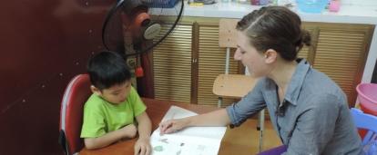 A Projects Abroad intern is seen helping a young boy read during her speech therapy internship in Vietnam.