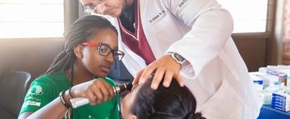 Une stagiaire Projects Abroad assiste un médecin avec l'auscultation d'une patiente pendant son stage à l'étranger. 