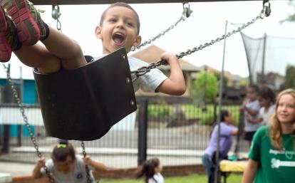 Children play on the swings under the supervision of a volunteer working with children in Costa Rica