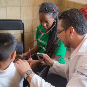 A student on a Spring Break Project in Mexico checks a child's pressure during a Public Health outreach