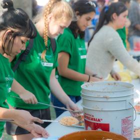 Refugee support volunteers serve a meal at a refugee camp in Mexico.