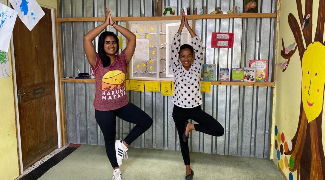 En volontär som åkt på en flexibel volontärresa lär ut yoga till en flicka i en kåkstad.