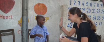 A Childcare volunteer in Ghana offers a child a high five for successfully completing an educational task. 