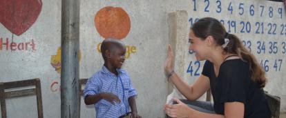 A Childcare volunteer in Ghana offers a child a high five for successfully completing an educational task. 