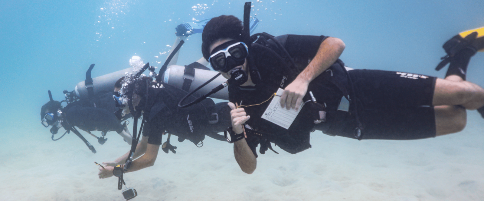 Three Projects Abroad divers swim alongside the camera, taking part in vital marine conservation work in Thailand